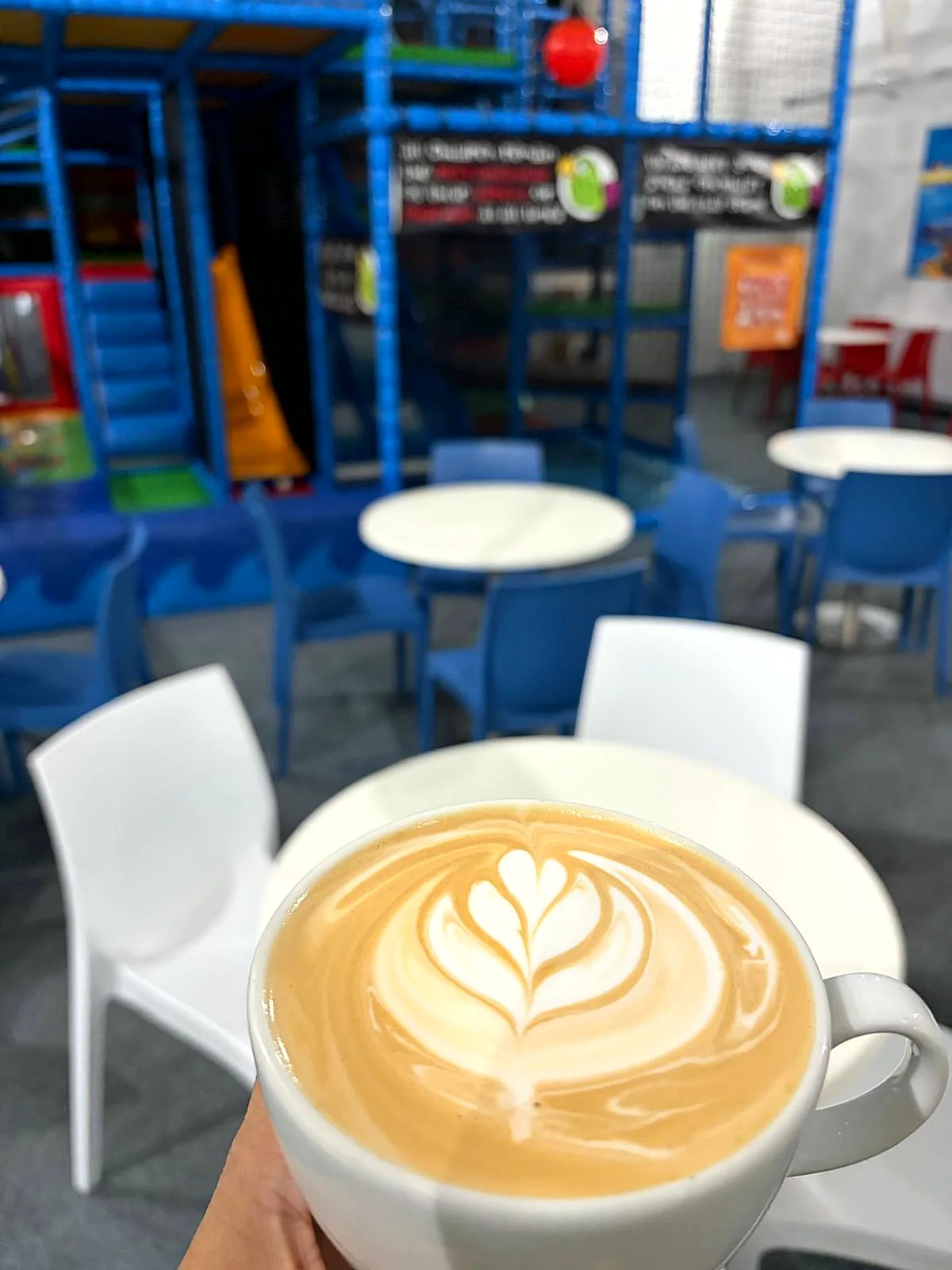 A freshly made flat white in the café, with the play frame behind