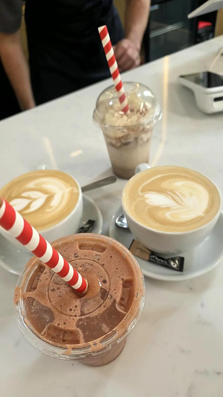Coffees and a milkshake on a caf&eacute; table